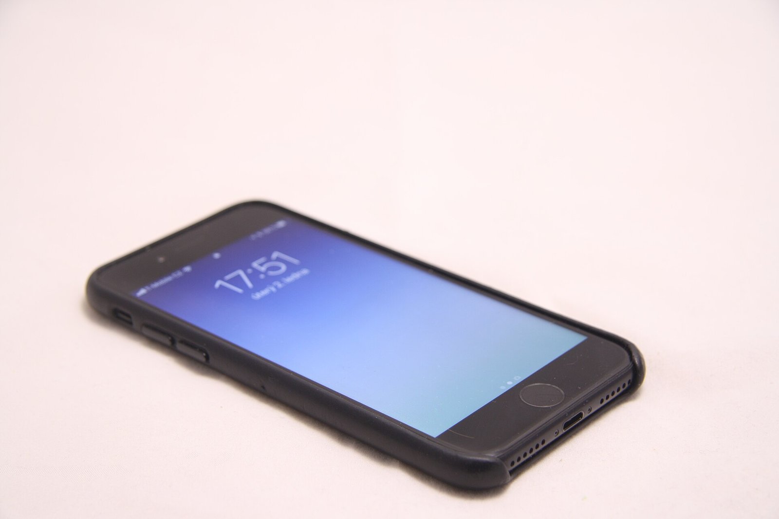 A smartphone lying face up in a black leather back case that wraps its sides and leaves the screen open.